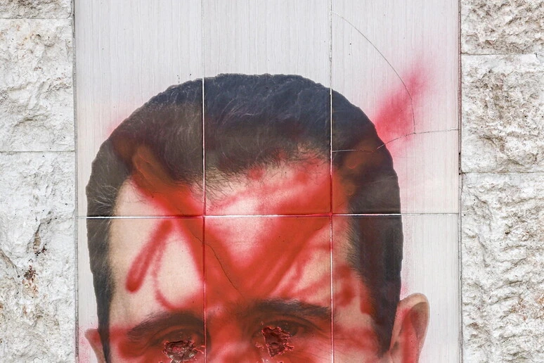 Ritratto di Bashar al-Assad imbrattato di vernice rossa su un muro in Siria
