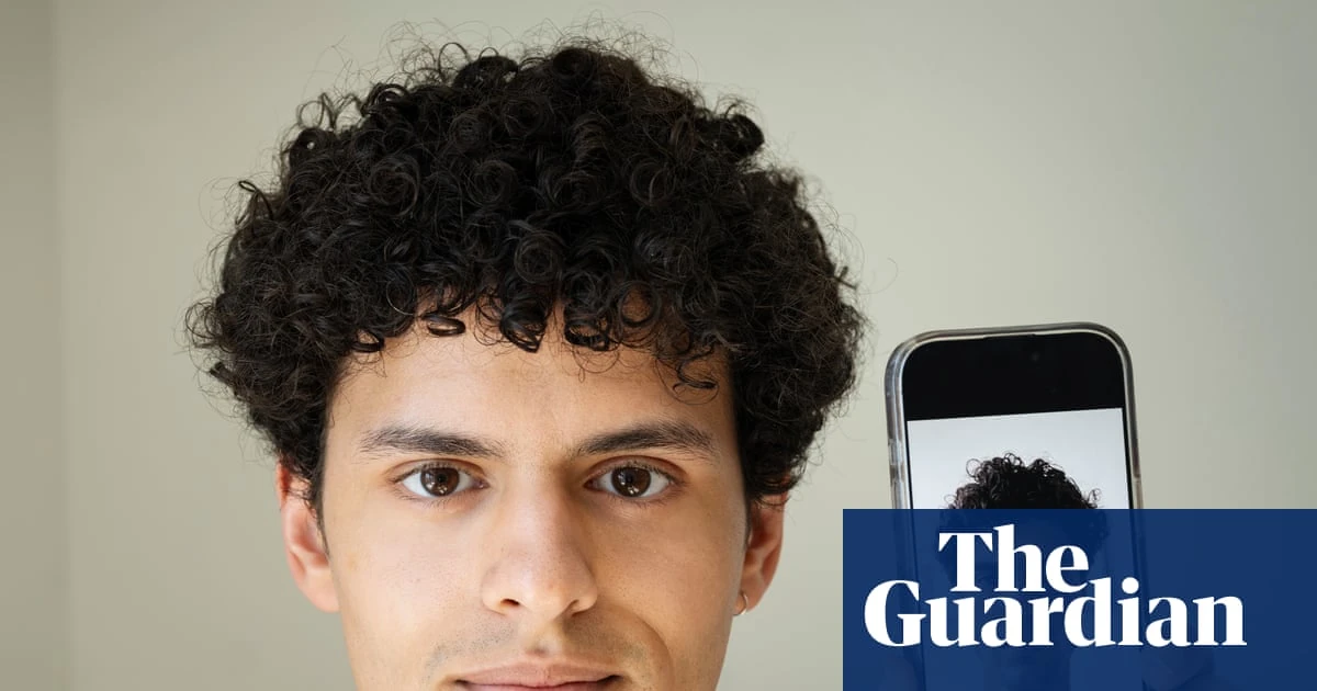 Un volto reale accanto a uno smartphone, immagine usata dal Guardian per raccontare l'AI face