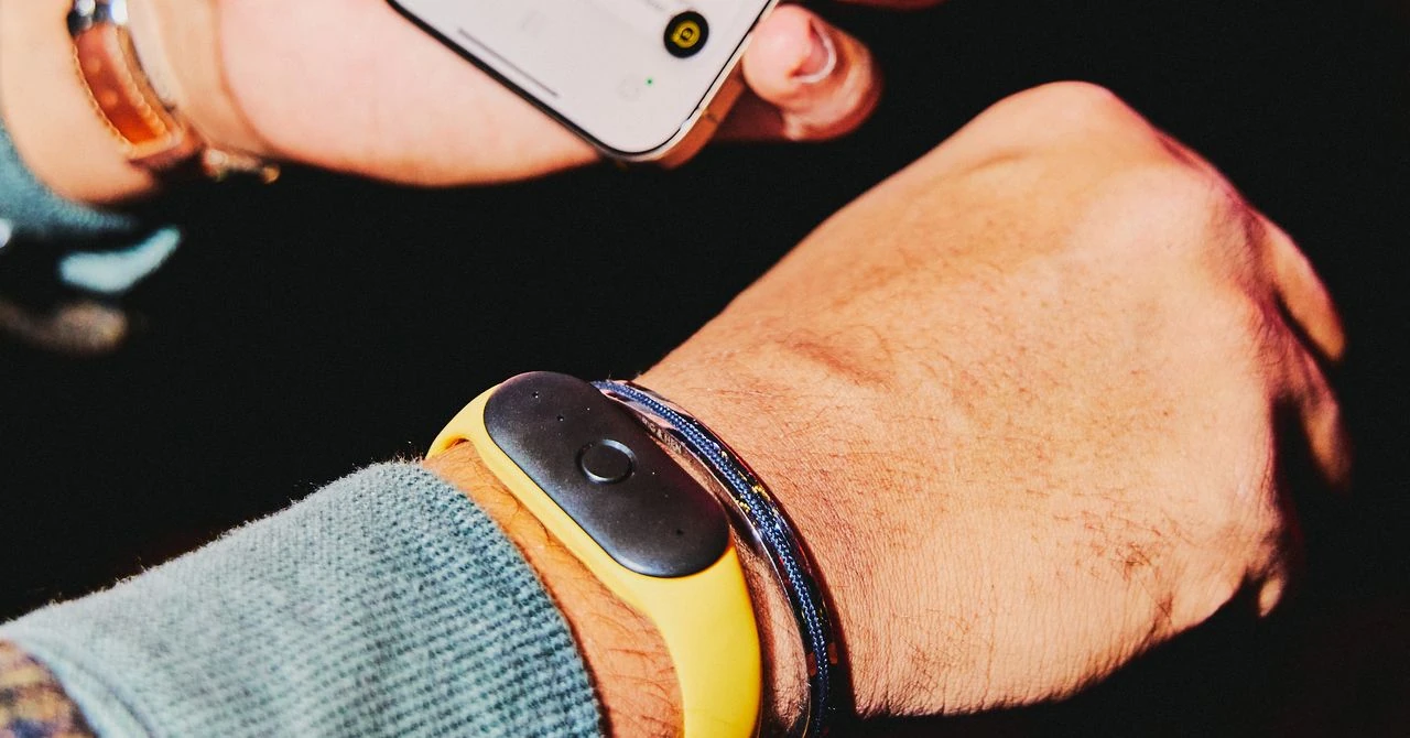 Un dispositivo wearable al polso accanto a uno smartphone