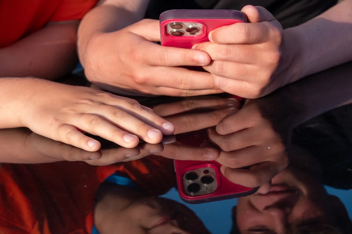 Le mani di alcuni ragazzini stringono uno smartphone