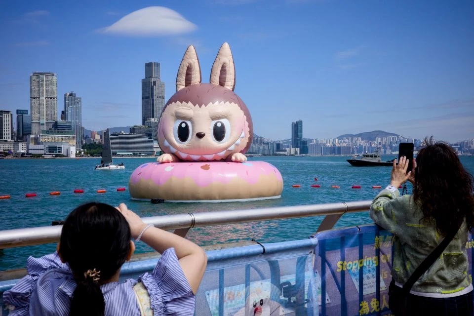 Un gigantesco Labubu gonfiabile galleggia nel porto di Hong Kong mentre i passanti lo fotografano