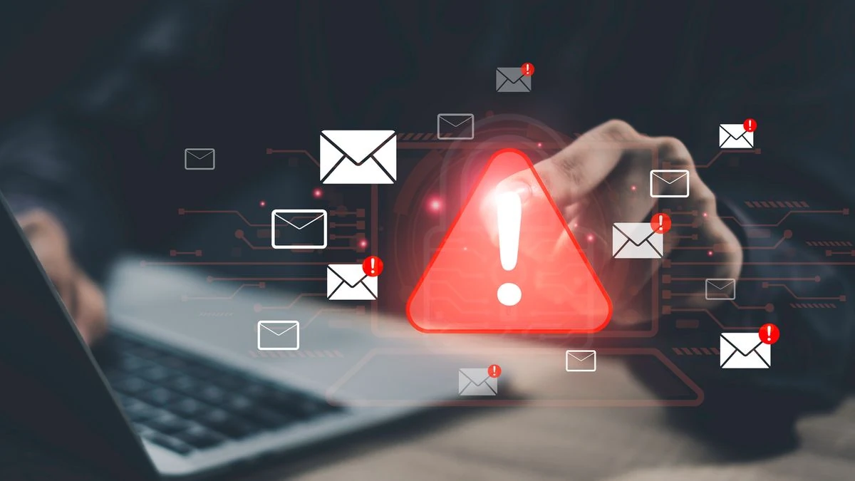 Allerta di sicurezza informatica: triangolo di pericolo e simboli di posta su un laptop
