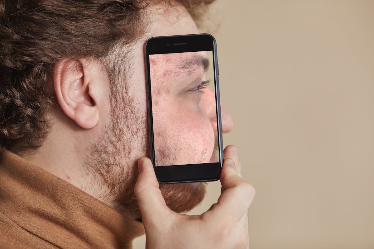Uomo tiene smartphone con riflesso del volto sullo schermo