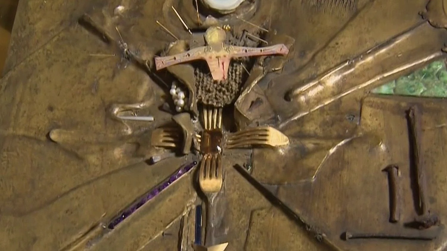 Dettaglio della copertina in bronzo de L'Apocalypse disegnata da Salvador Dalí, con crocifisso, forchette dorate e pietre