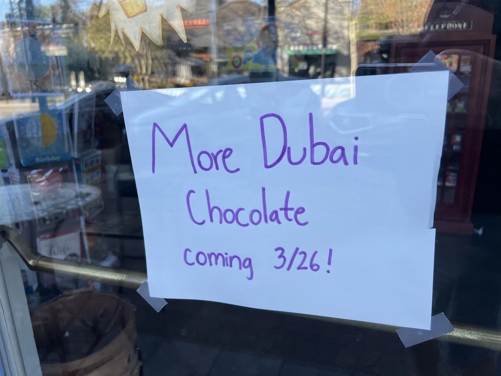 Cartello scritto a mano in una vetrina: More Dubai Chocolate coming