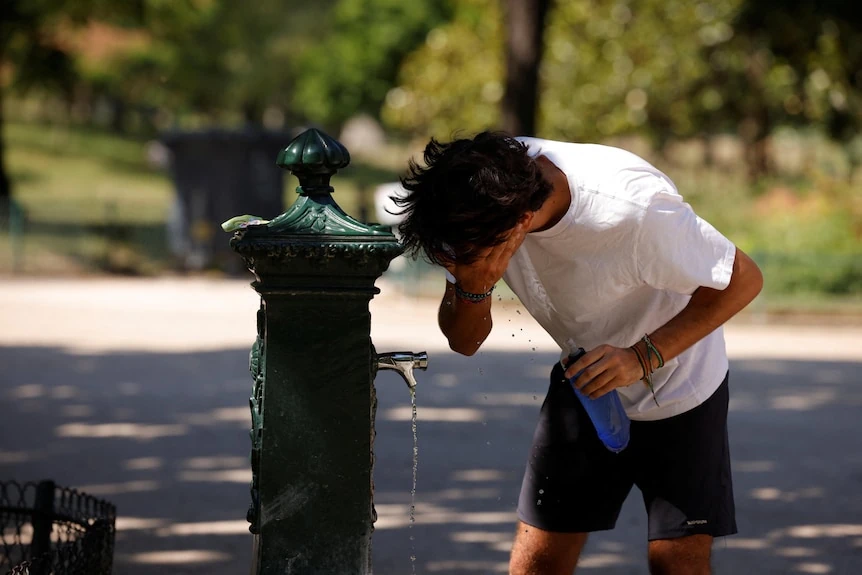 Un uomo si rinfresca il viso a una fontanella pubblica durante l'ondata di caldo