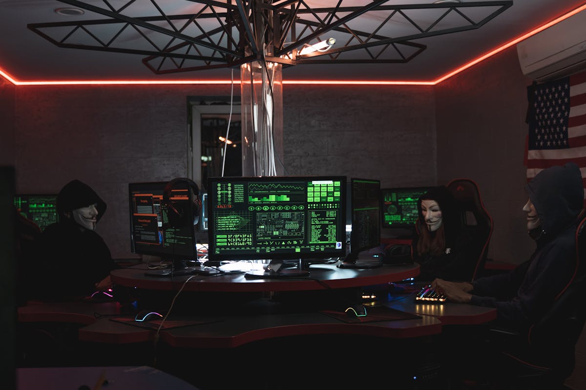 Team di esperti di cybersecurity al lavoro davanti a schermi di computer in una stanza buia