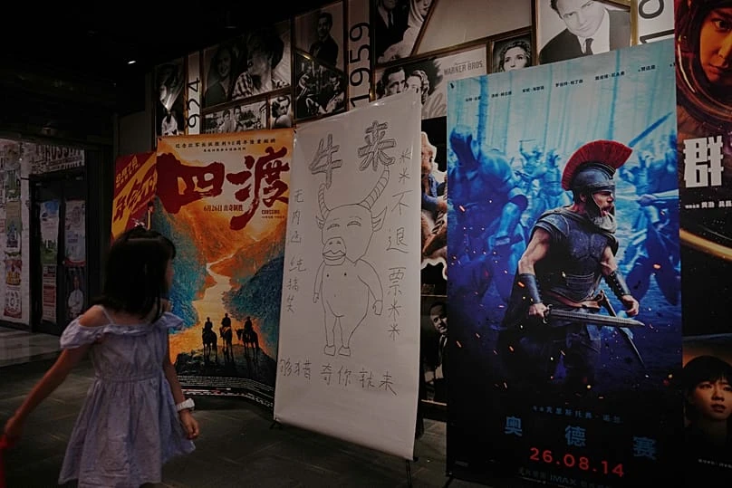 Il poster disegnato a mano di Niu Lai accanto a quello patinato di The Odyssey di Nolan nell'atrio di un cinema