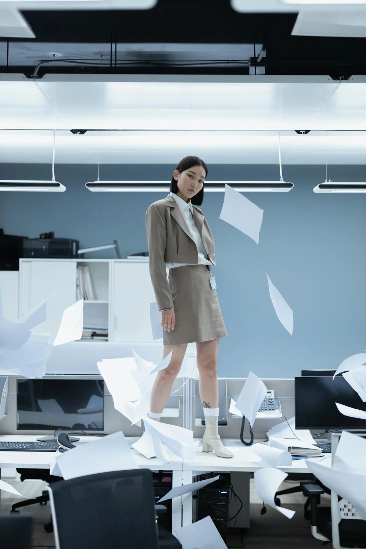 Donna stressata in ufficio con documenti che volano