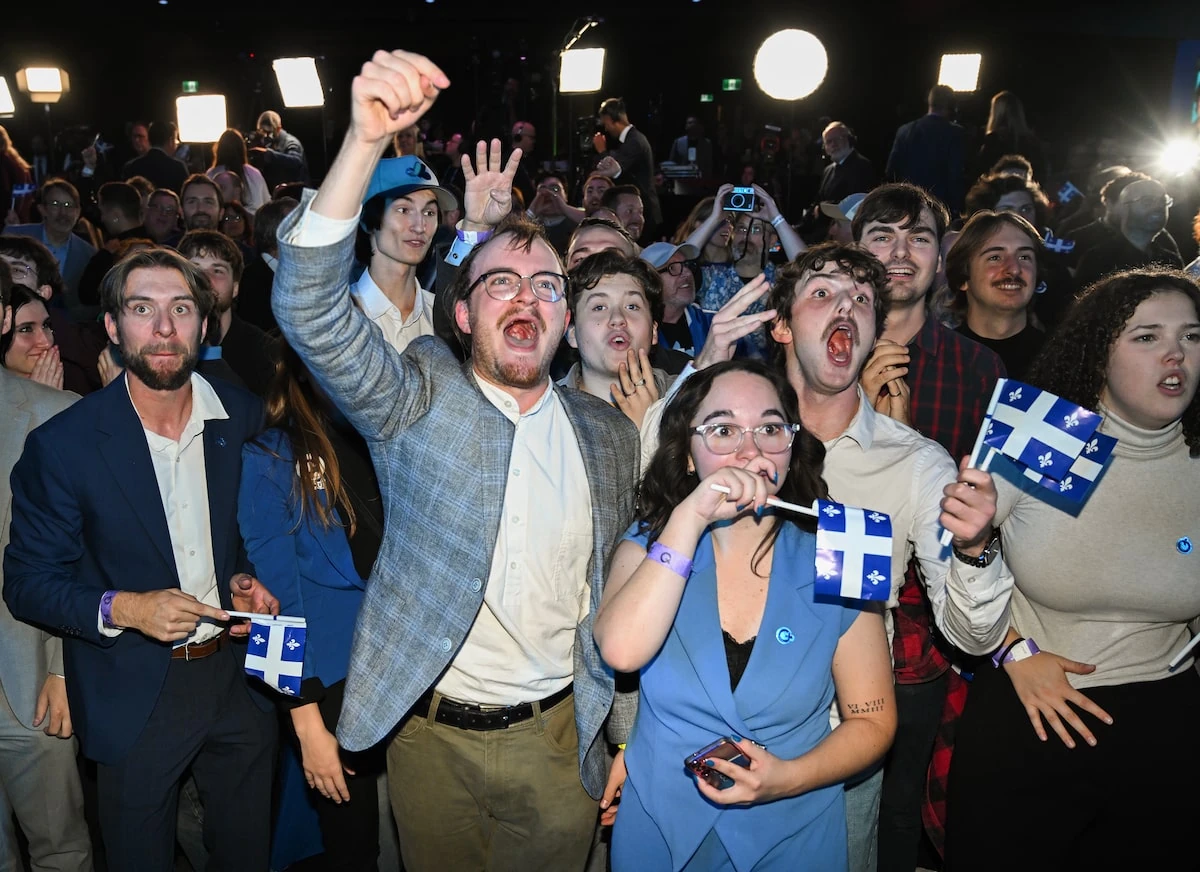 Sostenitori del Parti Québécois esultano con le bandiere del Québec durante la notte elettorale a Montréal