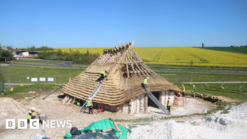 Volontari al lavoro sul tetto di paglia della Kusuma Neolithic Hall vicino a Stonehenge