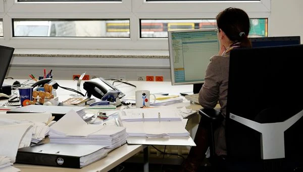 Postazione di lavoro in ufficio con scrivania piena di documenti