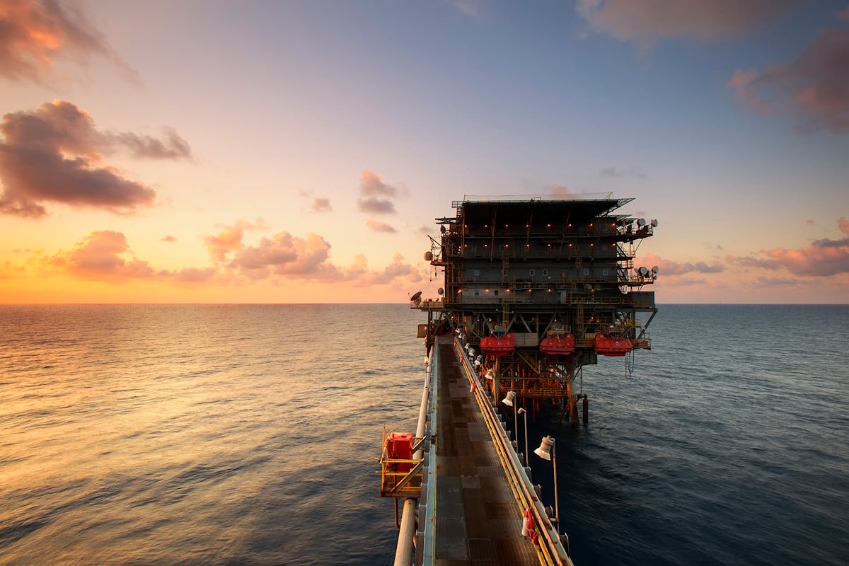 Piattaforma petrolifera offshore al tramonto, simbolo della dipendenza energetica