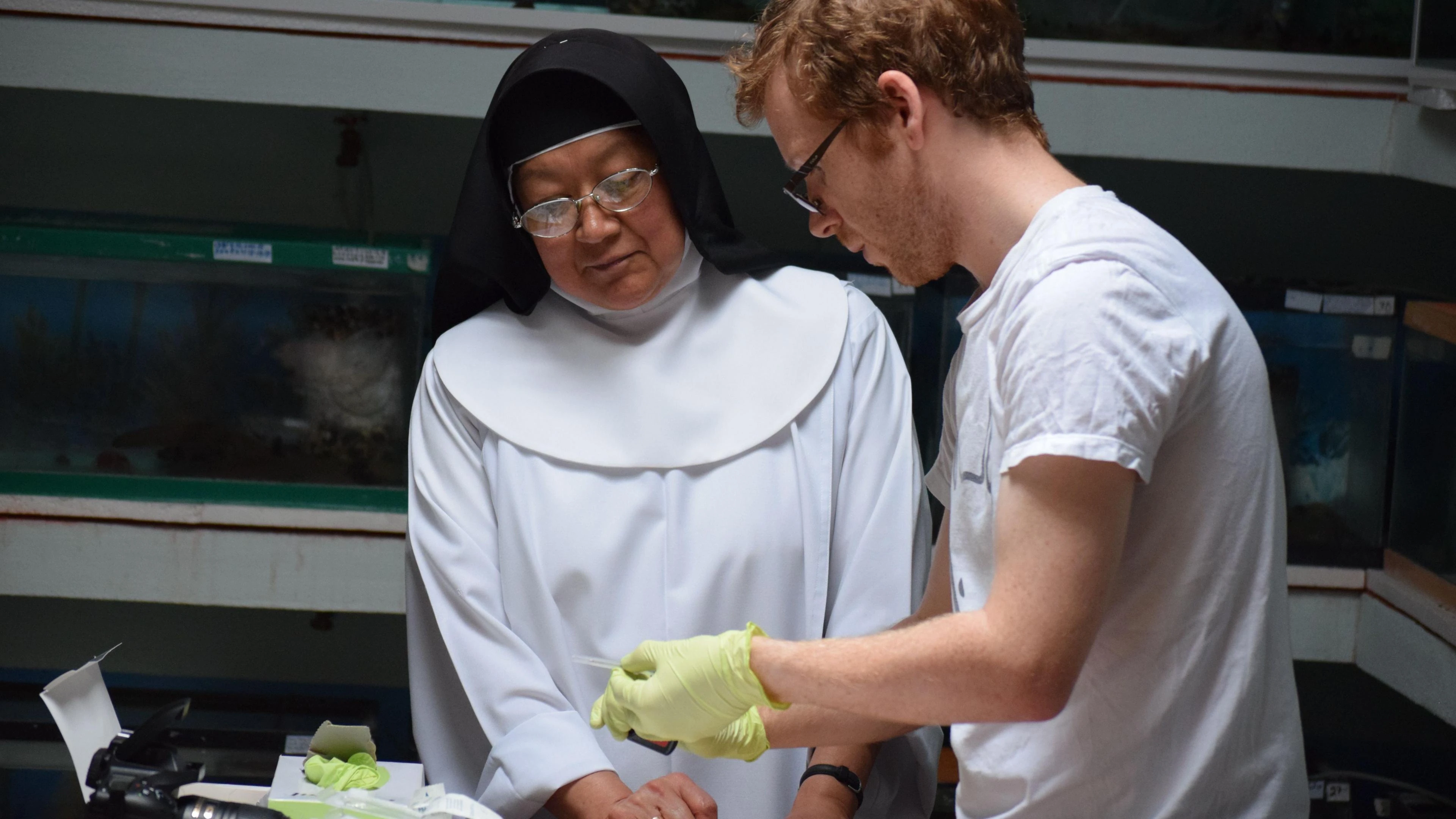 Una suora e ricercatori in laboratorio osservano materiale del progetto di conservazione