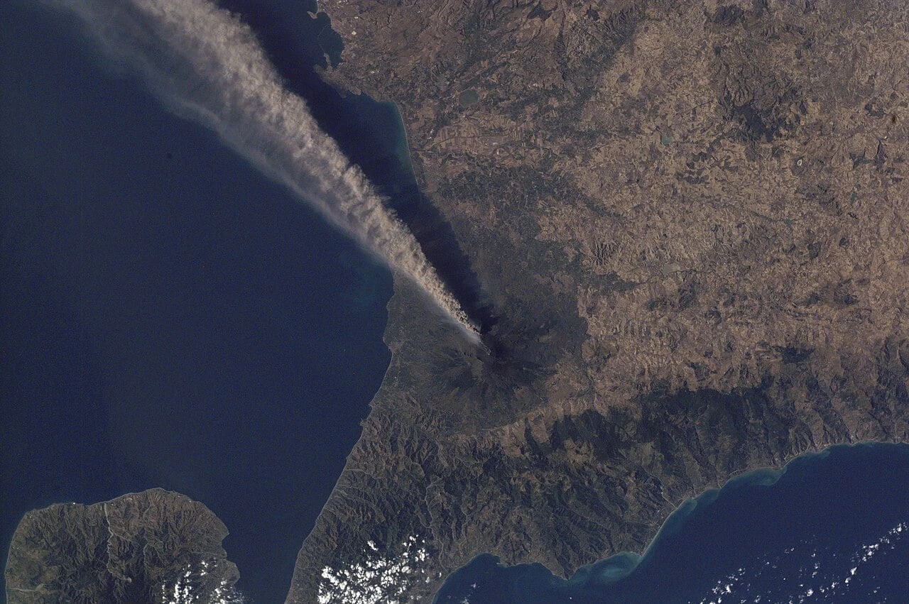 Il pennacchio di cenere dell'Etna visto dallo spazio, mentre si allunga sul mare verso la Sicilia