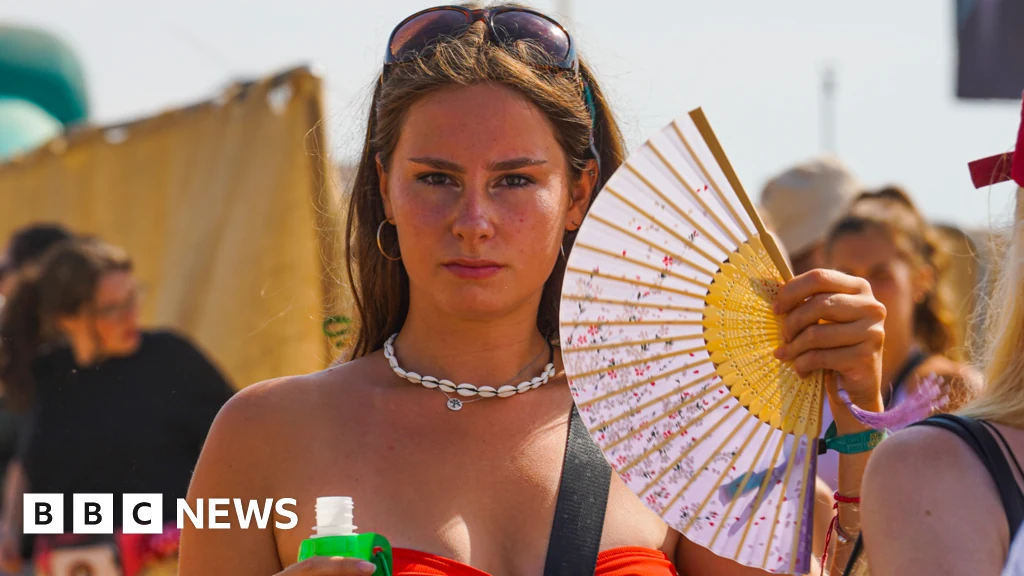 Ragazza a un festival estivo che usa un ventaglio per rinfrescarsi