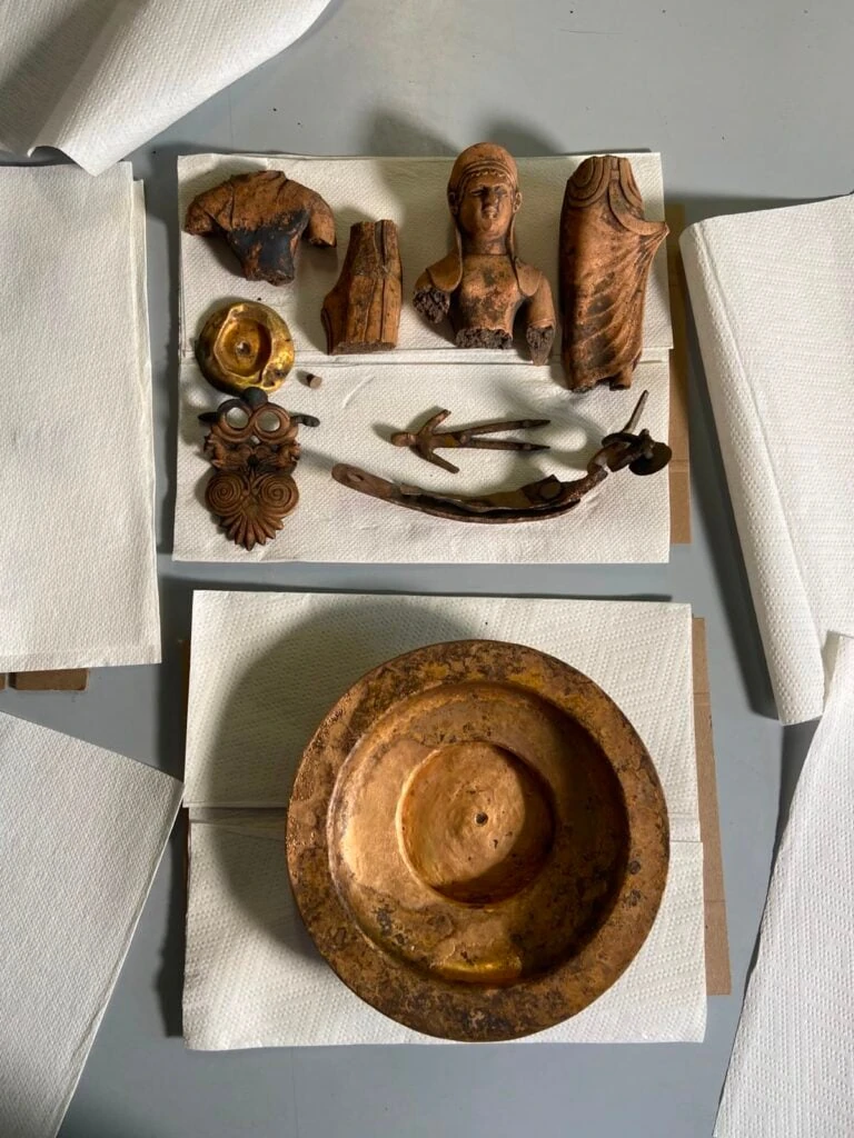 Il corredo di reperti bronzei e la statuetta femminile recuperati dal pozzo