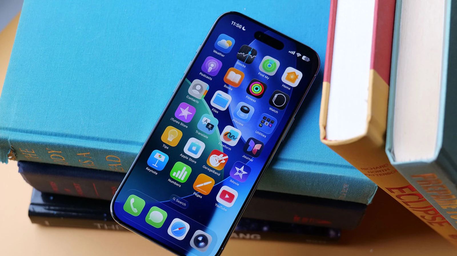 Un iPhone che mostra la schermata home di iOS appoggiato a una pila di libri