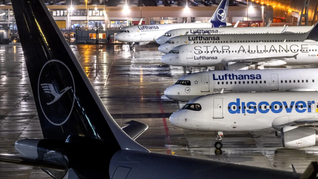 File di aerei di linea fermi in notturna sull'asfalto bagnato di un aeroporto